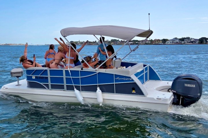People on a blue and white motorboat in clear water under a blue sky.