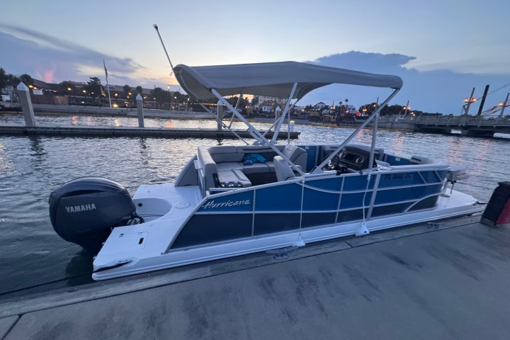 Pontoon boat docked at marina during sunset.