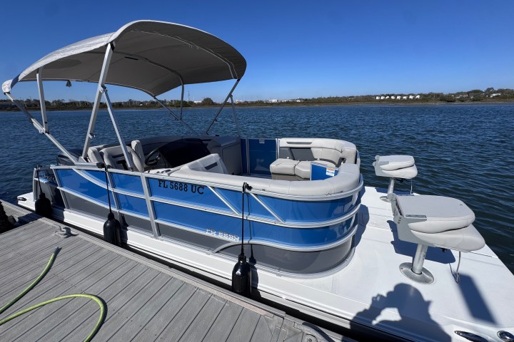 Blue and white pontoon boat docked on a sunny day.