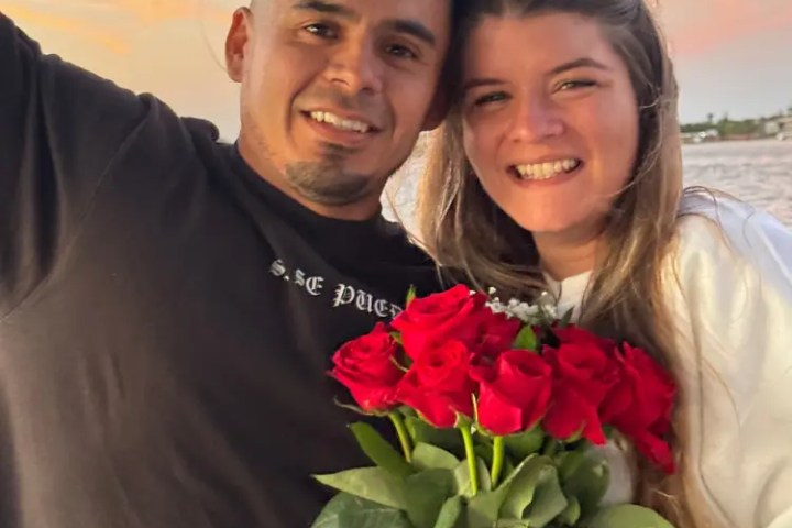 Smiling couple with roses at sunset on the beach.