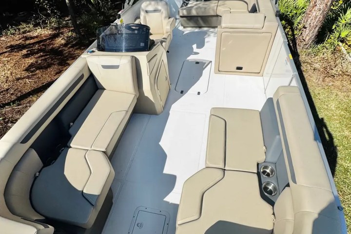 Empty beige seats on a boat with cup holders and a covered helm.