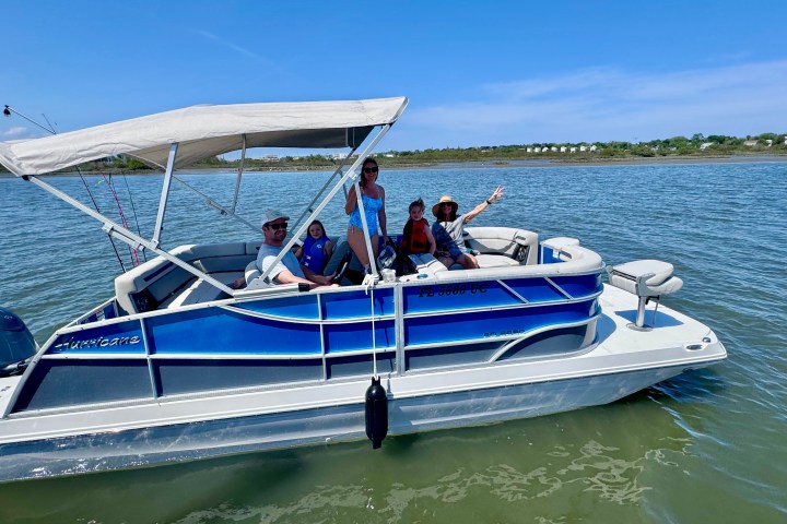 Group of people on a blue pontoon boat on a sunny day.