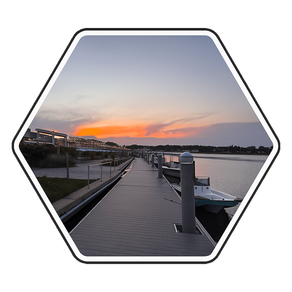 Hexagonal image of a sunset over a dock with boats and calm water.