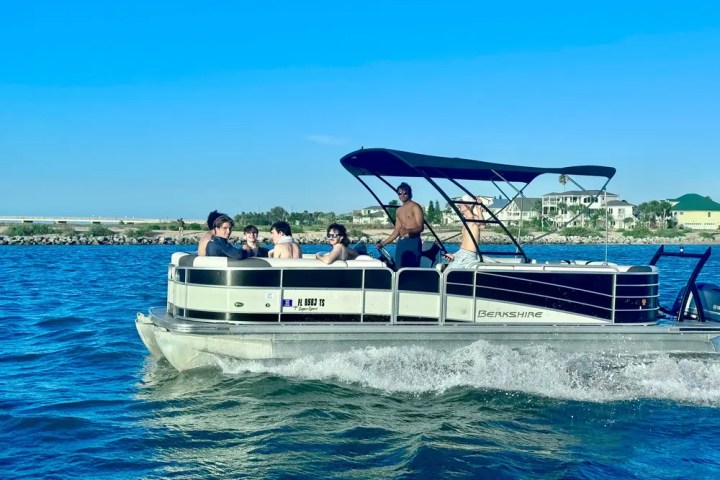 People enjoying a pontoon boat ride on the water with a clear blue sky.