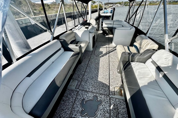 Interior of a docked boat with cushioned seating and a canopy overhead.