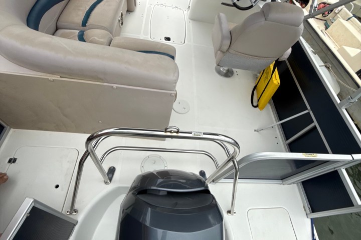 View of a boat interior with seating, steering wheel, and Yamaha 150 motor.