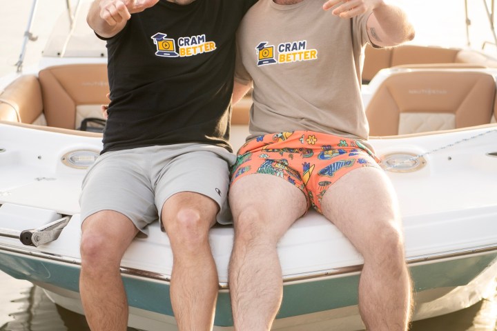 Two men sitting on a boat's edge, smiling and pointing at the camera.